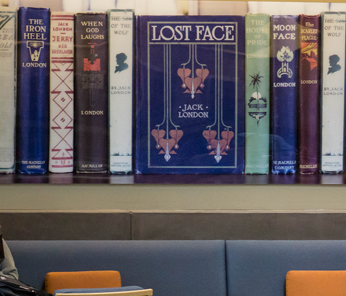 two students talk below a large wall art of spines of Jack London books